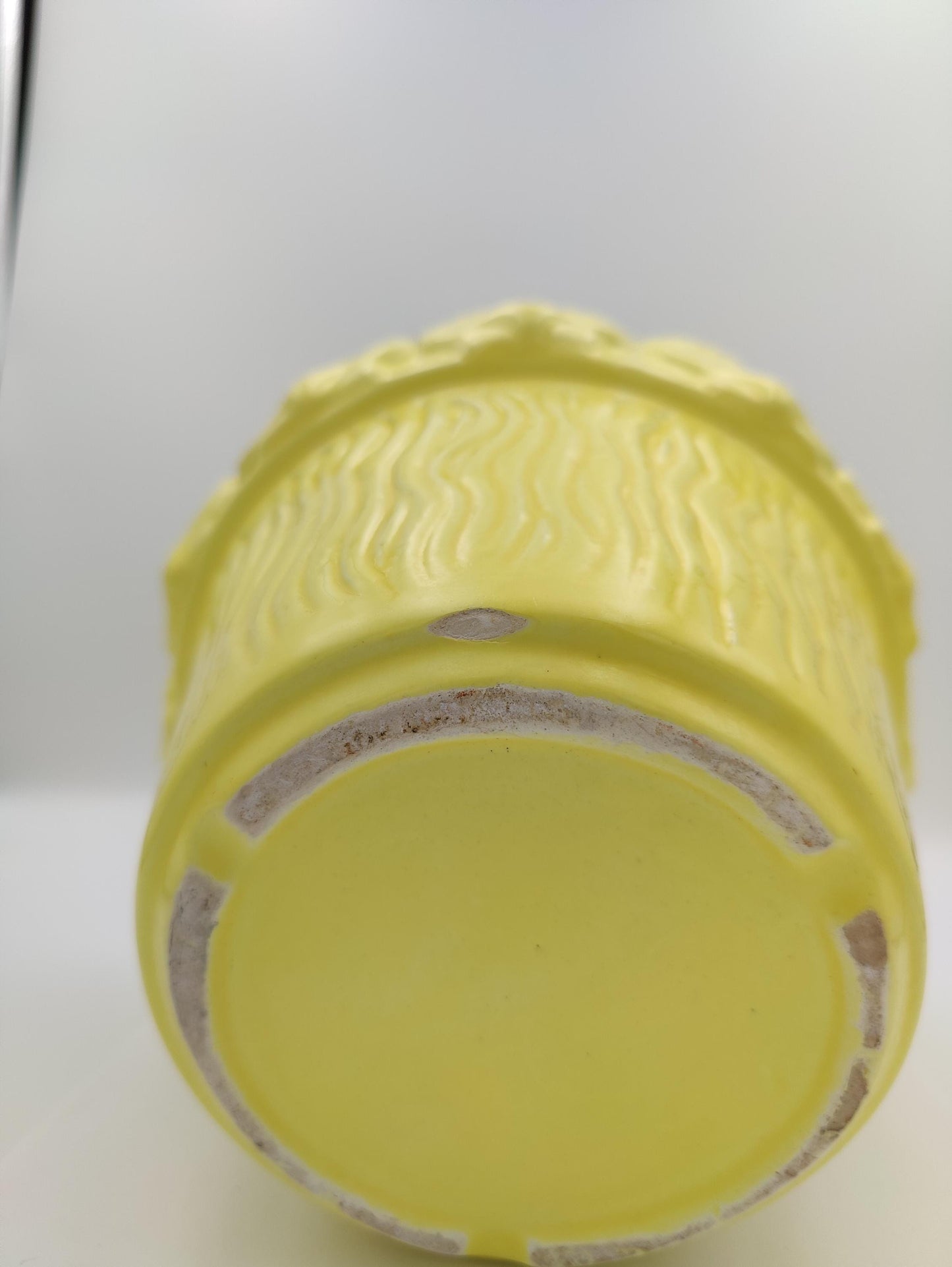 Light yellow mid sized planter has semi-thin vertical textured waves along face sides of the circular planter. 2" seashells ring around the lip. Stands about 6.5" H 8" D. few small noticable dings and one 1 inch..small chip on bottom