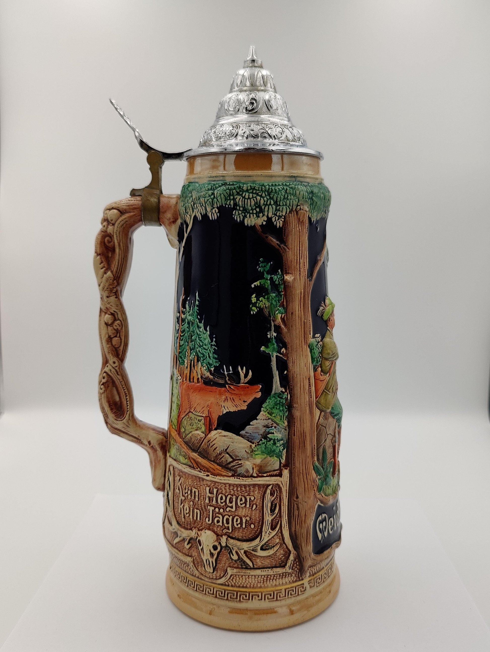 likely stoneware or ceramic with a pewter lid. Depicts a hunting scene with hunters and game.
Features the phrase &quot;Weidmanns Heil,&quot; a traditional German hunter&#39;s greeting. A valuable item for collectors of breweriana or German antiques.