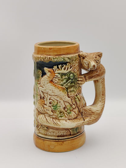 The item depicted is a vintage German-style beer stein,  made in Japan. Features a fox handle and the German phrase &quot;Des Jägers Freud,&quot; which translates to &quot;The Hunter&#39;s Joy.&quot; . It has a bear on/as the handle